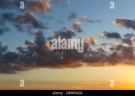 Dunkle Wolken bei Sonnenuntergang trennen den blauen Himmel von dem bereits orangen Glanz über dem Wasser der Ostsee in Kolobrzeg in Polen Stockfoto