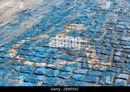 Rollstuhl, der den Behindertenparkplatz symbolisiert, wurde auf gepflasterter Fahrbahn blau und weiß gestrichen. Stockfoto