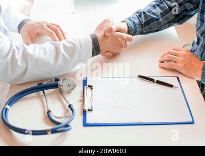 Patient und Arzt schütteln die Hände nach Unterzeichnung eines Krankenversicherungsvertrags. Konzept Der Gesundheitspflege. Stockfoto