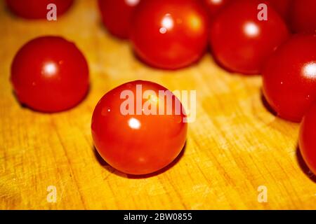 Kleine rote Kirschtomaten auf einem Holzbrett. Nahaufnahme Stockfoto