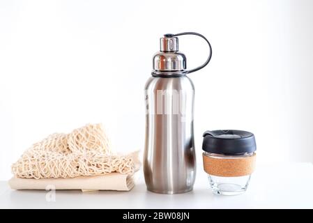 Umweltfreundliche Einkaufstaschen, wiederverwendbare Glas Kaffeetasse, wiederverwendbare Wasser Edelstahl Flasche auf weißem Hintergrund. Nachhaltiger Lebensstil. Konzept ohne Kunststoff und ohne Abfall. Stockfoto