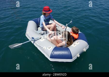 Drei Kinder haben Spaß in einem Schlauchboot Stockfoto