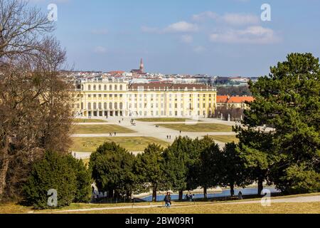 Wien, Österreich - 8. März 2017: Blick auf Menschen, die durch den Schönbrunner Garten mit Schloss Schönbrunn und Wien im Hintergrund laufen Stockfoto