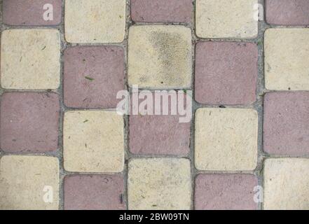 Draufsicht auf den roten und gelben Hintergrund des Bürgersteiges. Vollrahmen aus regelmäßigen quadratischen Kopfsteinpflaster in Linien Stockfoto