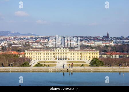 Wien, Österreich - 8. März 2017: Menschen, die durch den Schönbrunner Garten mit Schloss Schönbrunn und Wien im Hintergrund laufen Stockfoto