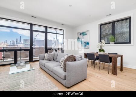 2020: Ein moderner Wohn- und Essbereich mit deckenhohen Fenstern und Blick auf das Hancock Building in Downtown Chicago. Stockfoto