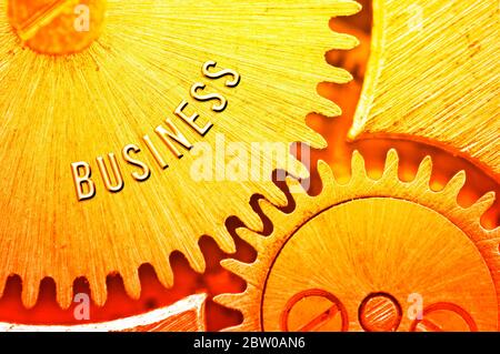 Goldene Zahnräder. Goldener Hintergrund mit der Inschrift GESCHÄFT auf Zahnrädern. Konzeptionelles Foto für Business Design. Konzept von Reichtum, Erfolg, Ewigkeit, Stockfoto