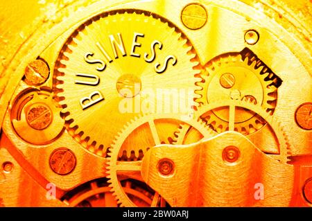 Goldene Zahnräder. Goldener Hintergrund mit der Inschrift GESCHÄFT auf Zahnrädern. Konzeptionelles Foto für Business Design. Konzept von Reichtum, Erfolg, Ewigkeit, Stockfoto