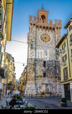 Brescia, Italien, 11. September 2019: Torre della Pallata Backstein mittelalterlichen Uhrturm Gebäude mit Merlonen in typisch italienischen Straße, Brescia historischen Zentrum, blauer Himmel, vertikale Ansicht, Lombardei Stockfoto