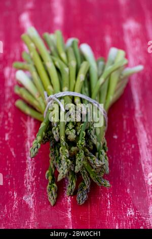 Grüner Spargel auf einem roten Tisch Stockfoto