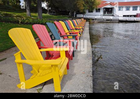 Glan Orchard, Ontario / Kanada - 10/05/2008: Abnehmende Perspektive von mehrfarbigen Muskoka Stühlen in der Seeufer des Touristenortes Stockfoto