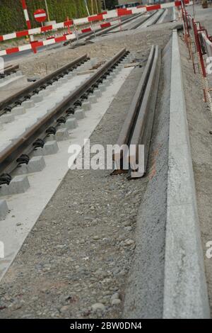 Neue Tramschienen im Boden auf Betonsockel und einige Ersatzschienen daneben installiert. Eine Szene von einer Tiefbaustelle. Stockfoto