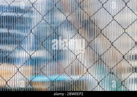 Eisengittergewebe, das durch die Oberfläche eines Kunststoffbleches scheint, um als Textur für den Hintergrund verwendet werden. Stockfoto