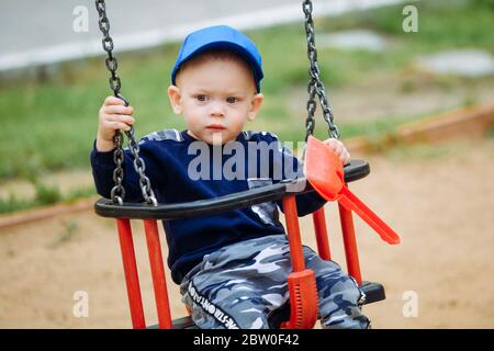 Schönes Kind 1-2 Jahre alt Reiten eine Schaukel und hält Spielzeug in den Händen Stockfoto