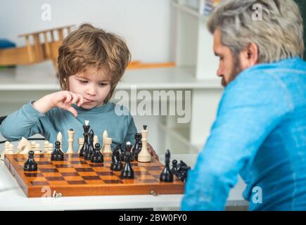 Vater und Sohn spielen Schach. Lehrer hilft seinem Schüler Jungen mit Schach auf Bildungsklasse Stockfoto