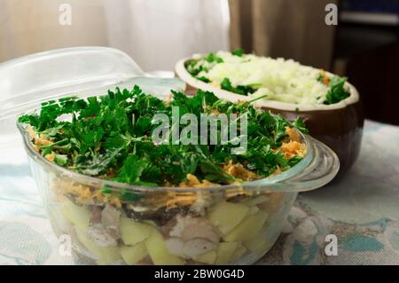 Kartoffeln in Töpfen zum Backen vorbereiten. Kartoffeln, Fleisch, Zwiebeln, Karotten, Petersilie, Pilze, Käse in Glas und Keramikgefäßen. Ländliche Küche Stockfoto
