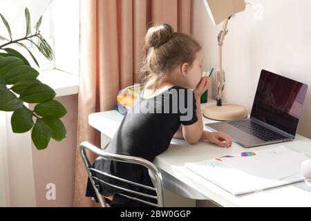 Neugierige kleine Mädchen mit Laptop auf dem Schreibtisch Stockfoto
