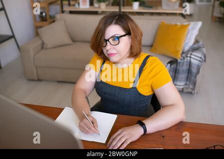 Konzentrierte behinderte Student Mädchen in Brille Schreiben Sie Vorlesung während Online-Kurs auf dem Computer Stockfoto