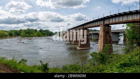 Eine Eisenbahnbrücke aus Stein und Metall, die den Broad River in Columbia, South Carolina überquert, vom Columbia Canal und Riverfront Park Stockfoto