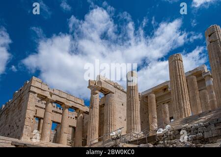 Akropolis von Athen, Griechenland Wahrzeichen. Propylaea Eingangstor leer, Altgriechisch Säulen und Treppen, niedrige Winkel Blick, blau bewölkten Himmel. Stockfoto