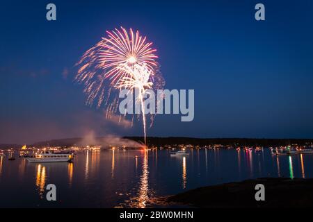 Boothbay Harbor, Maine, USA - 4. Juli 2019: Boote im Hafen bei Dämmerung während des Feuerwerks, Zeitlupe, Bewegungsunschärfe Stockfoto