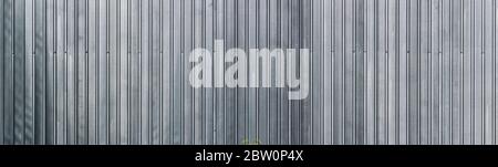Panoramasicht auf die profilierte Blechwand. Graue Metalloberfläche. Nahtloser Hintergrund. Stockfoto