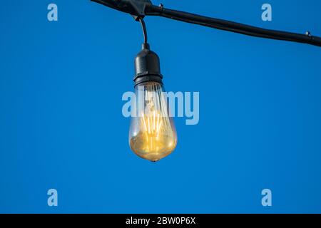 Gestylte runde Glühbirnen für dekorative Beleuchtung bei Nacht gegen blauen Himmel. Stockfoto