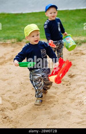 2 Zwillingsbrüder 1-2 Jahre mit Sand auf dem Spielplatz spielen Stockfoto