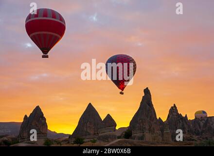 Heißluftballons, die bei Sonnenaufgang am Himmel schweben Stockfoto