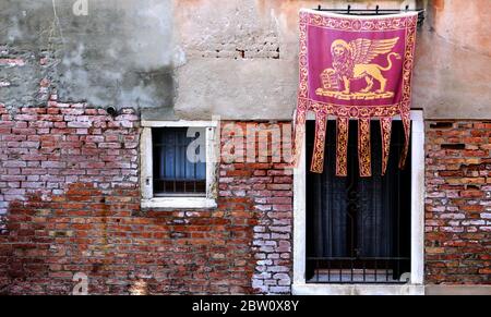 Die venezianische Flagge mit dem symbolischen 'geflügelten Löwen', bekannt als das Banner des Hl. Markus, ist stolz ausgestellt. Stockfoto