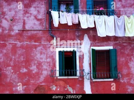 Gewaschen Tücher hängen an einer bunten Wand auf der Insel Burano, Italien, berühmt für seine exquisite Spitze Herstellung Tradition. Stockfoto
