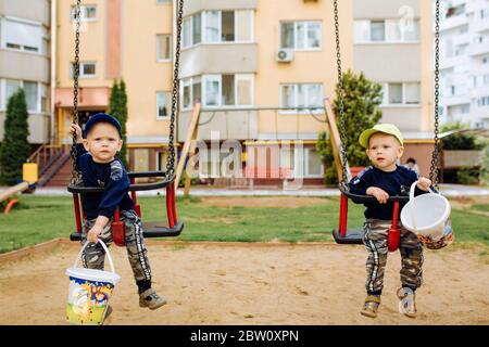 2 Zwillingsbrüder reiten zusammen auf einer Schaukel, 1-2 Jahre Stockfoto