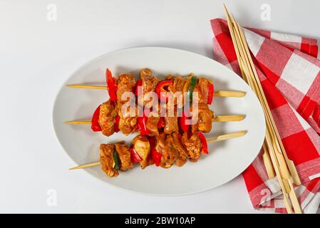 Rohes mariniertes Hühnerfleisch auf Holzspießen, Schwein, Huhn, Rindfleisch in weißem Teller auf weißem Hintergrund. Stockfoto