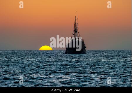 Ein altes Piratenschiff aus Holz sitzt am Meer bei Sonnenuntergang Silhouette gegen den Sonnenuntergang Himmel Stockfoto