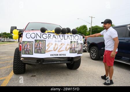 Luis Reyes, Vater von Victor Reyes, zeigt auf das Banner seines Sohnes, als die Absolventen der Navarro Early College High School sich darauf vorbereiten, durch ihre Nachbarschaft im Norden von Austin, Texas, zu marschieren, um ein akademisches Finale zu feiern, das durch die Coronavirus-Pandemie verkürzt wurde. Stockfoto