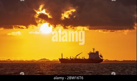 Öltanker fährt an der Küste von Belize in Mittelamerika. Sonnenuntergang. Schöner gelb-oranger Sonnenuntergang im Hintergrund Stockfoto