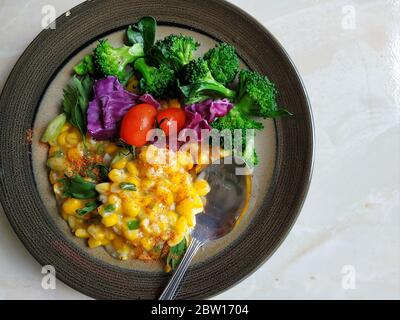 Indonesisches Maismehl mit Brokkoli, Tomaten und in Scheiben geschnittenem ​​purple-Kohl auf dem Teller serviert Stockfoto