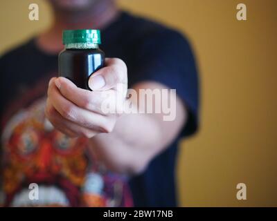 Ein Mann hält eine Flasche Essenz von Huhn. Nahrungsergänzungsmittel helfen, die Gesundheit zu erhalten. Stockfoto