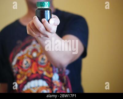 Ein Mann hält eine Flasche Essenz von Huhn. Nahrungsergänzungsmittel helfen, die Gesundheit zu erhalten. Stockfoto