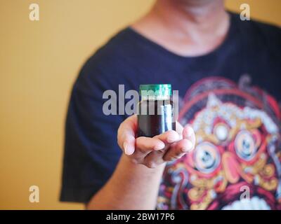 Ein Mann hält eine Flasche Essenz von Huhn. Nahrungsergänzungsmittel helfen, die Gesundheit zu erhalten. Stockfoto