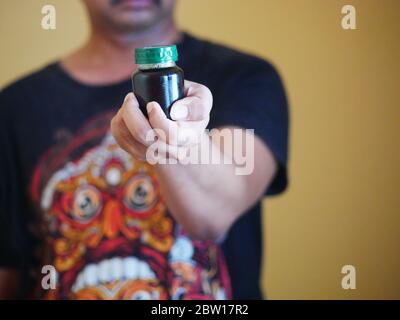 Ein Mann hält eine Flasche Essenz von Huhn. Nahrungsergänzungsmittel helfen, die Gesundheit zu erhalten. Stockfoto