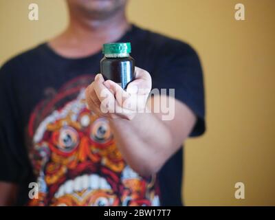 Ein Mann hält eine Flasche Essenz von Huhn. Nahrungsergänzungsmittel helfen, die Gesundheit zu erhalten. Stockfoto