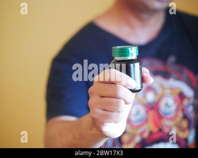 Ein Mann hält eine Flasche Essenz von Huhn. Nahrungsergänzungsmittel helfen, die Gesundheit zu erhalten. Stockfoto