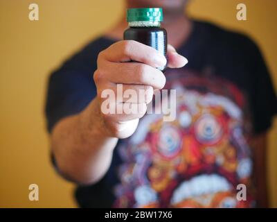 Ein Mann hält eine Flasche Essenz von Huhn. Nahrungsergänzungsmittel helfen, die Gesundheit zu erhalten. Stockfoto