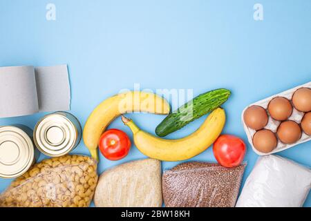 Lieferkost. Reis, Buchweizen, Nudeln, Dosenfutter, Zucker, Toilettenpapier auf blauem Hintergrund. Sammeln Sie freiwillig Lebensmittel. Spende, Coronavirus Quarantin Stockfoto