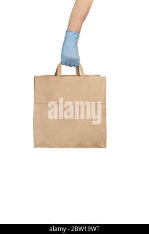 Lieferung Mann in medizinischen Handschuhen hält Papier Handtasche mit Lebensmitteln. Coronavirus Lebensmittel Lieferung. Freiwilliger bringt eine Schachtel mit Essen. Spende, Quarantäne Konz Stockfoto