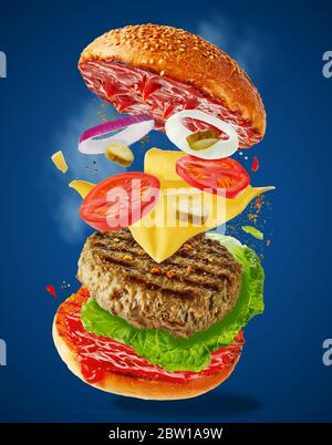 Großer leckerer hausgemachtes Burger mit fliegenden Zutaten auf blauem Hintergrund. Konzept der Levitation von Lebensmitteln. Stockfoto