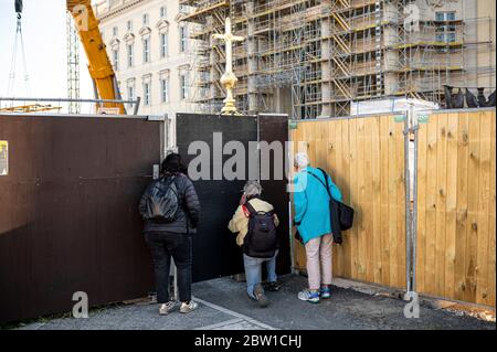 Berlin, Deutschland. Mai 2020. Zuschauer versuchen, durch den Bauzaun einen Blick auf das Kreuz für die Kuppel des Humboldt Forums zu bekommen. Das umstrittene Kreuz soll am Freitag auf dem weitgehend abgeschlossenen Humboldt Forum platziert werden. Quelle: Fabian Sommer/dpa/Alamy Live News Stockfoto