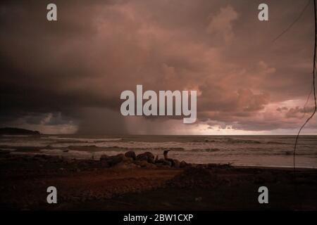 Stürmische Regenwolken und Niederschläge über dem Indischen Ozean sind von einem Strand in Bengkulu, an der Westküste von Sumatra, Indonesien, zu sehen. Stockfoto