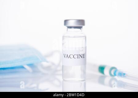 Immunisierung Medicare Konzept. Nahaufnahme von Impfstoff Fläschchen mit verschwommenen Schuss und Masken hinter isoliert auf weißem Hintergrund Stockfoto